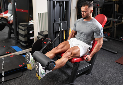 Bodybuilder doing leg extensions photo