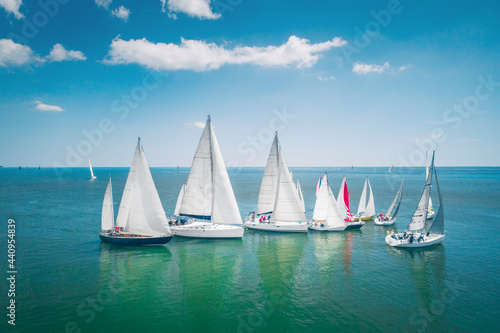 Fototapeta Naklejka Na Ścianę i Meble -  Regatta sailing ship yachts with white sails at opened sea. Aerial view of sailboat in windy condition