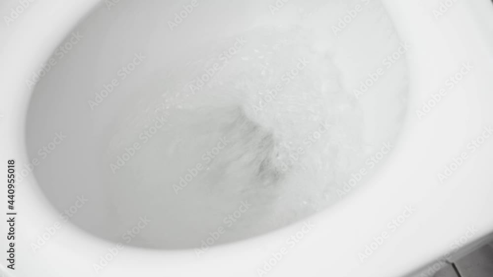 the water is flushed into the white toilet the water is flushed into the white toilet