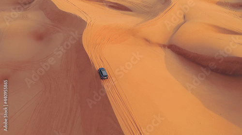 AERIAL. Hight flight above car. Desert safari car sand dunning in the Dubai desert during sunset