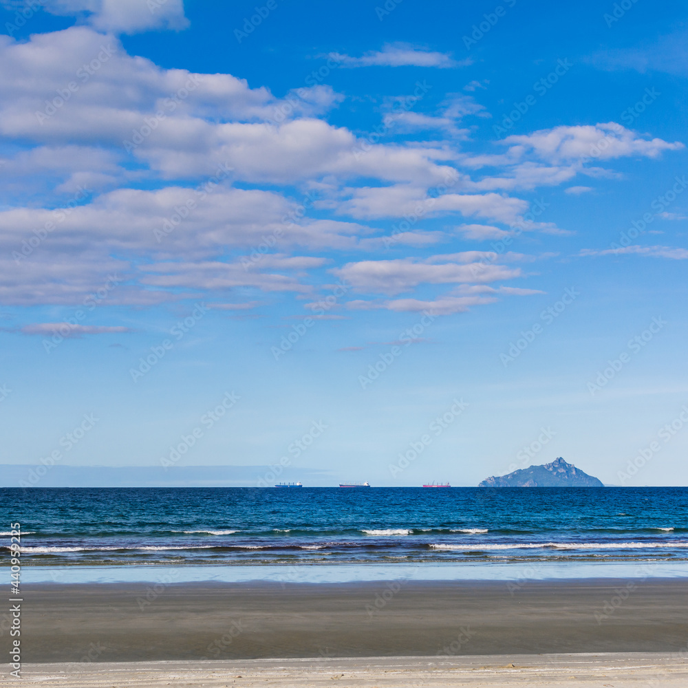 A string of cargo ships sailing along horizon A string of cargo ships sailing along horizon
