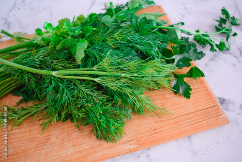 Fresh herbs are on the table. Dill and parsley on a wooden board