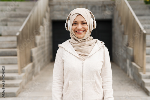 Middle eastern woman in hijab listening music with wireless headphones