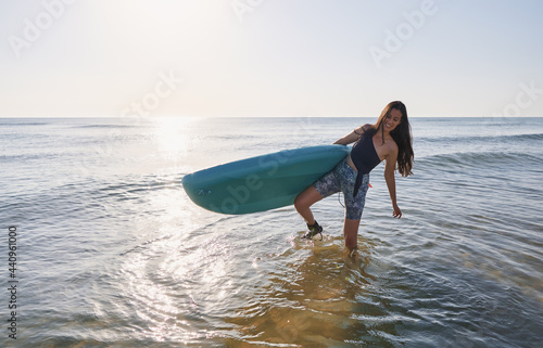 Happy girl on the beach with a paddle surf board