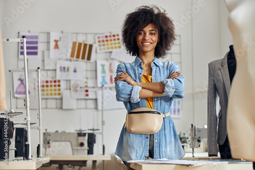 African-American entrepreneur with crossed hands poses for camera in sewing workshop photo