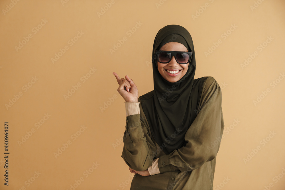 Black muslim woman in hijab smiling and pointing finger aside Black muslim woman in hijab smiling and pointing finger aside
