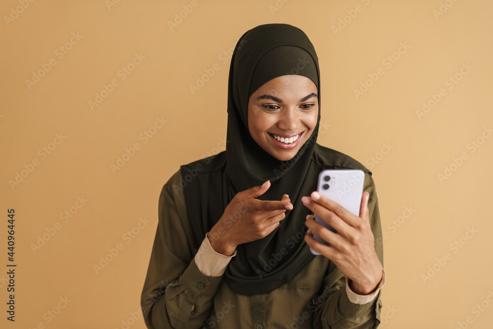 Black muslim woman in hijab using and pointing finger at mobile phone Black muslim woman in hijab using and pointing finger at mobile phone