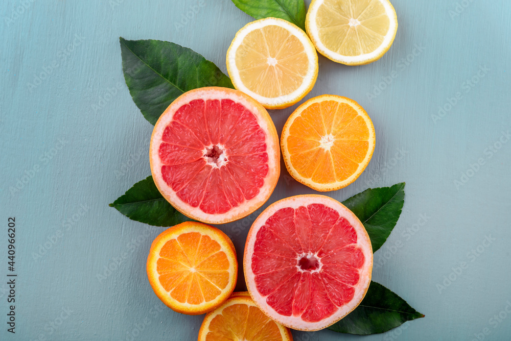 Top view of colorful fruit slices with citrus leaf arrangement. Summer tropical juice concept with lemon, grapefruit and orange on vintage blue table. Flat lay. Fresh smoothie beverage menu background Top view of colorful fruit slices with citrus leaf arrangement. Summer tropical juice concept with lemon, grapefruit and orange on vintage blue table. Flat lay. Fresh smoothie beverage menu background