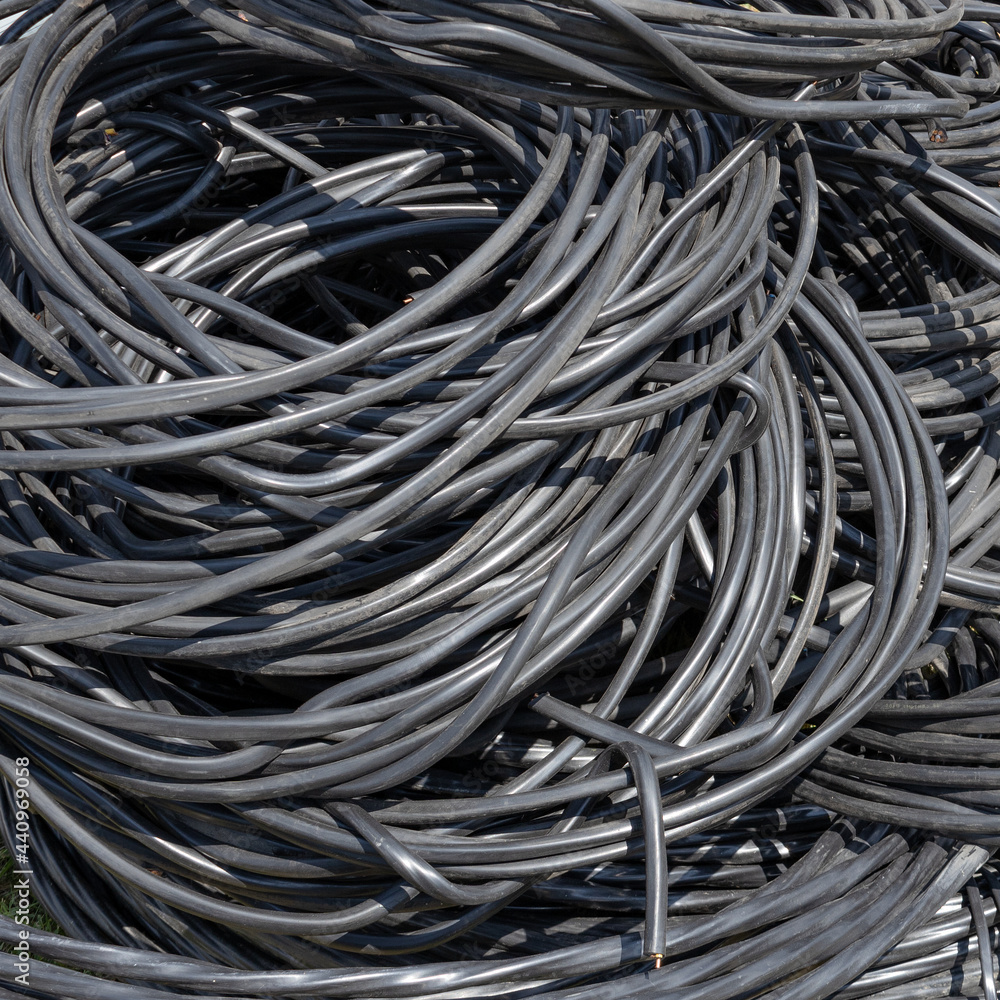 A twisted copper wire in black plastic insulation lies in a pile. Electrification and automation of systems. Consumable material. A twisted copper wire in black plastic insulation lies in a pile. Electrification and automation of systems. Consumable material.