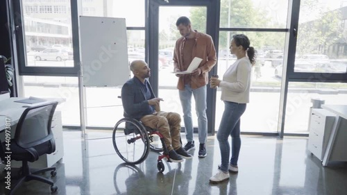 man holding folder with charts near handicapped african american boss and woman