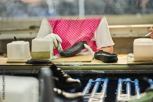 Detail of worker applying glue to the shoes sole in a production