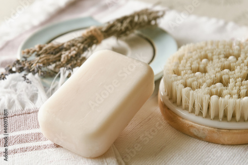Handmade organic white soap with body brush and aroma herbs close up. Bath accessories on a white towel. Daily body care concept, organic bath products  