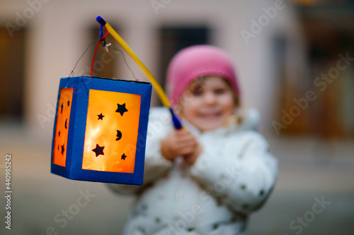 Close-up of little kid girl holding selfmade lanterns with candle for St. Martin procession. Healthy toddler child happy about children and family parade in kindergarten. German tradition Martinsumzug photo