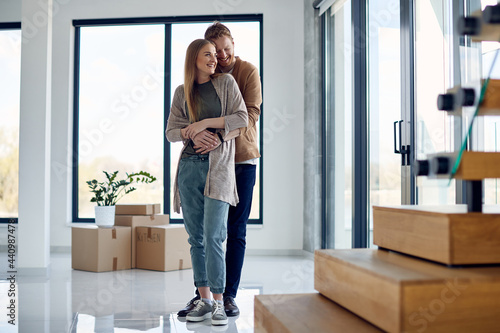 Young carefree couple standing embraced in their new apartment.