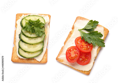Tasty crackers with cheese, tomatoes and cucumber on white background