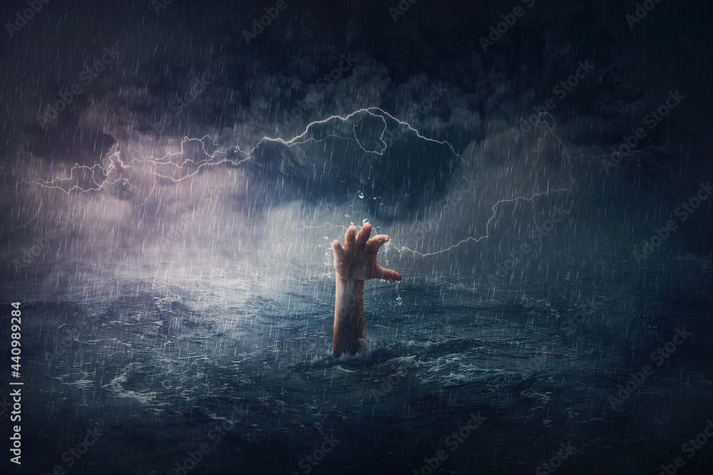 Arm drowning in the sea. Surreal and dramatic scene of person hand sinking in the ocean under a hurricane stormy weather. People need help in risk situations. Despair, depression and failure metaphor