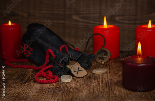 Gebo rune, a bag of runes, and a background of candles with selective focus.The meaning of the rune that fell out during divination: to unite, without encroaching on each other's freedom, mutual love. photo