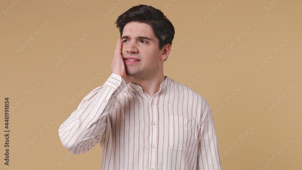 Excited puzzled pensive brunet man 20s years old wears white striped shirt looks around thinks scratches at temple comes up with ideas raised finger isolated on pastel beige background studio portrait Excited puzzled pensive brunet man 20s years old wears white striped shirt looks around thinks scratches at temple comes up with ideas raised finger isolated on pastel beige background studio portrait