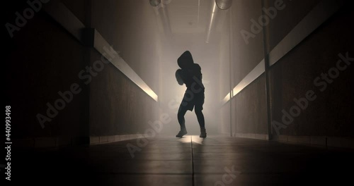 Boxer boxing with a shadow in a semi-dark corridor with a backlight behind his back, slow motion. Videos for motivation, goal achievement, success photo