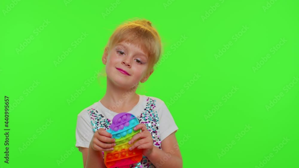 Cute girl playing with pop it sensory anti-stress toy. Chroma key. Child kid presses on colorful rainbow squishy bubbles. Stress anxiety relief. Trendy fidgeting game for stressed children and adults Cute girl playing with pop it sensory anti-stress toy. Chroma key. Child kid presses on colorful rainbow squishy bubbles. Stress anxiety relief. Trendy fidgeting game for stressed children and adults