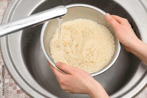 Foto Woman rinsing rice in sifter under running water