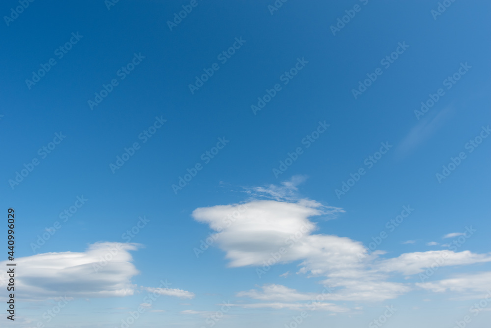 Fototapeta premium Blue sky with light fluffy swirling white clouds. Perfect natural sky background for your photos