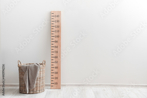 Wooden stadiometer with basket near light wall photo