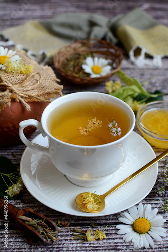 Close-up white cup with chamomile tea and honey on a wooden background. Vertical