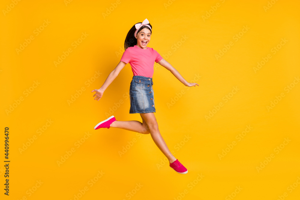Photo of impressed shiny school girl wear pink t-shirt smiling jumping high isolated yellow color background Photo of impressed shiny school girl wear pink t-shirt smiling jumping high isolated yellow color background