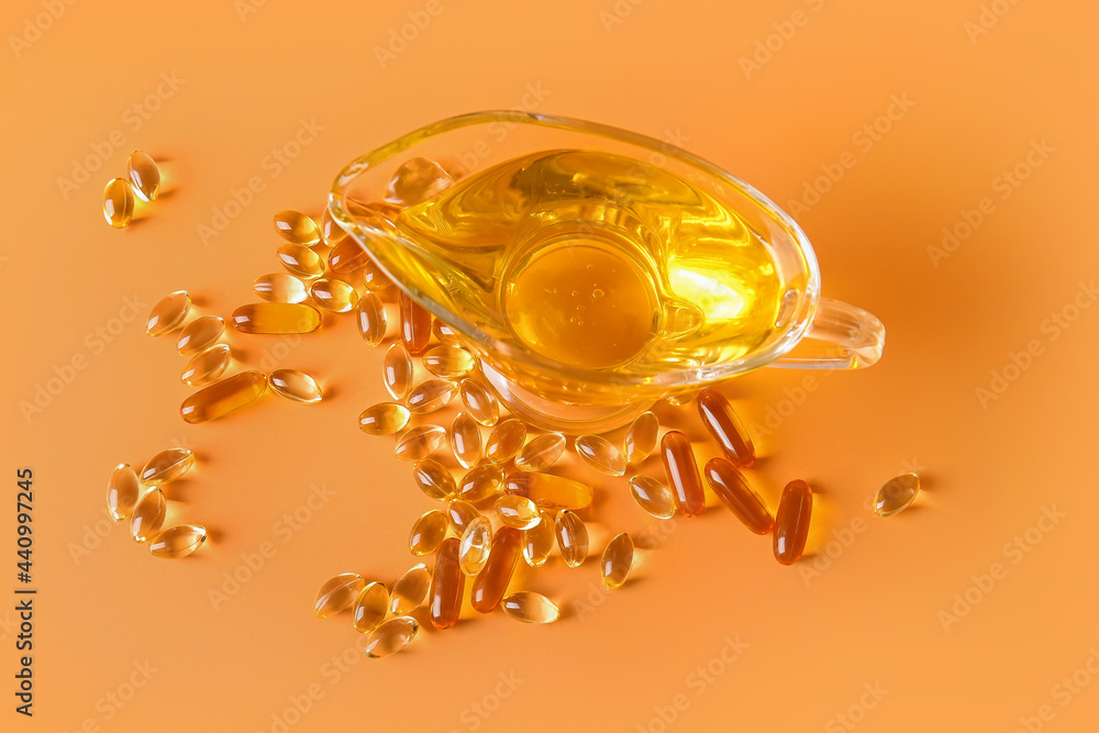Gravy-boat of fish oil and capsules on color background