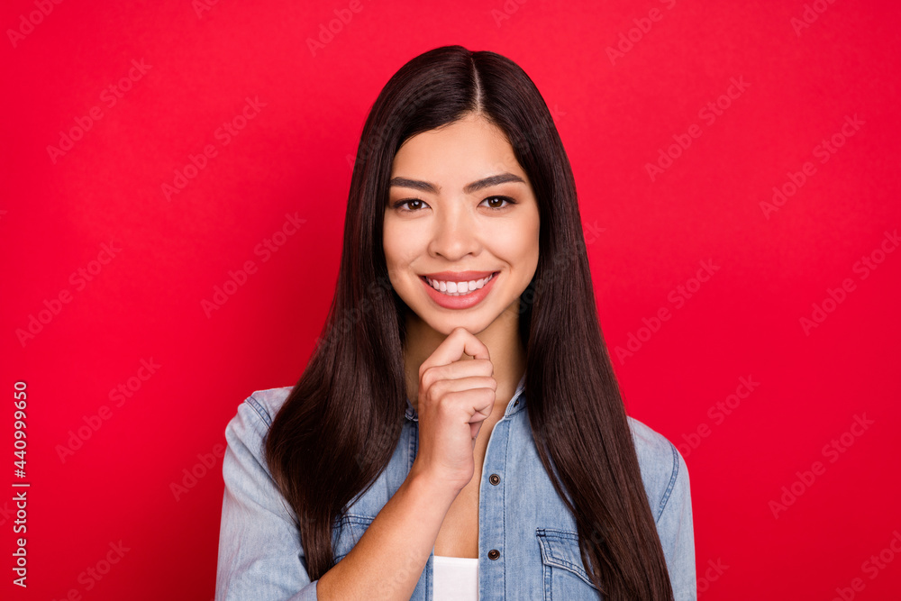 Photo of young cheerful asian girl happy positive smile hand touch chin dream think isolated over red color background Photo of young cheerful asian girl happy positive smile hand touch chin dream think isolated over red color background