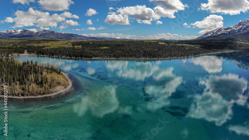 Kathleen Lake, Yukon, Canada. Taken in the summertime with stunning emerald, turquoise green reflective water with blue sky clouds and wild boreal forest. Beautiful Canadian landscape in nature. 