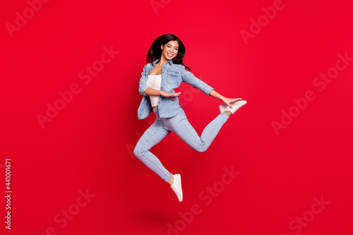 Full length body size view of pretty fit cheerful girl jumping dancing having fun isolated over bright red color background