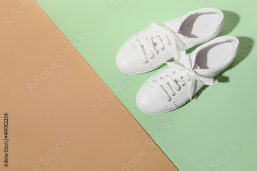 White female gumshoes for sport outfit on beige and green color background with copy space. View from above. photo