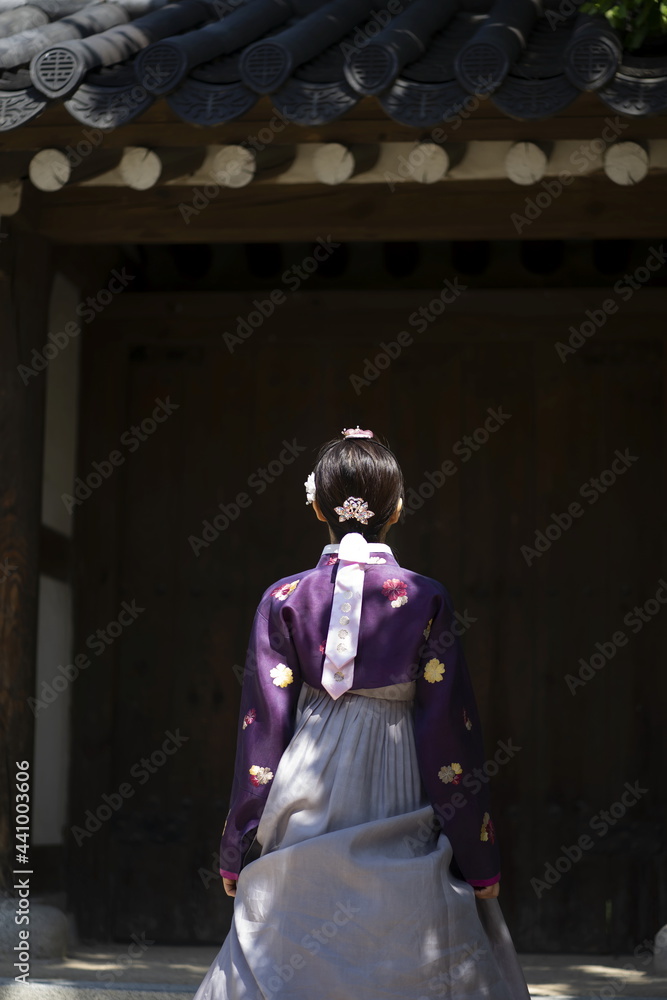 Woman in Korean traditional clothes standing in front of Korean traditional gate Woman in Korean traditional clothes standing in front of Korean traditional gate