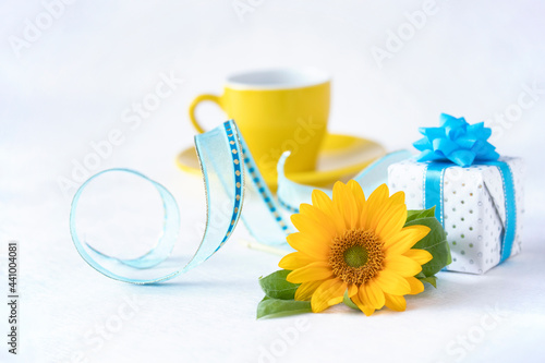 青いリボンのプレゼントとコーヒーとヒマワリの花