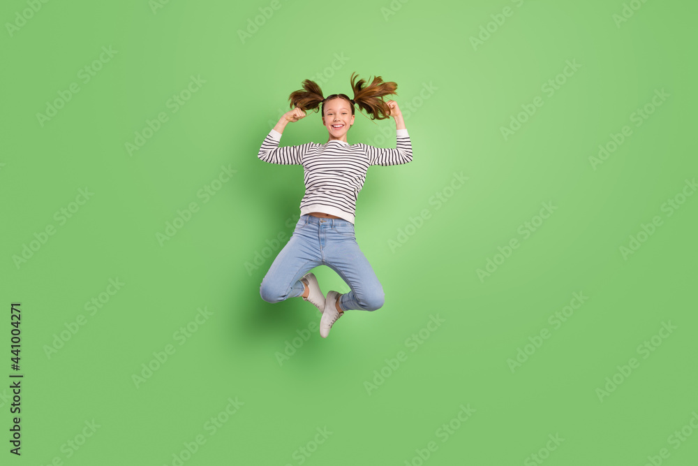 Photo of sweet strong small schoolgirl dressed striped sweater showing muscles jumping high isolated green color background
