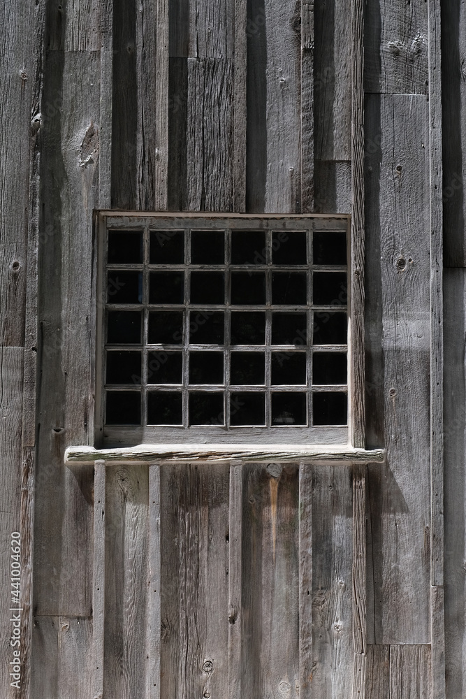 Thirty segment window in weathered wooden wall