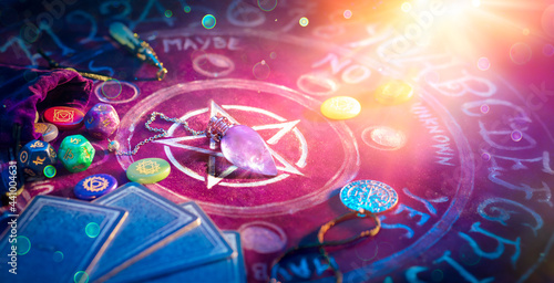 Fotografia Cartomancy And Tarot - Pendulum On Altar With Defocused Cards And Chakra Stones