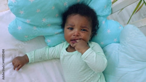 a yawning baby boy American-African lies on the bed on a blue cotton bed