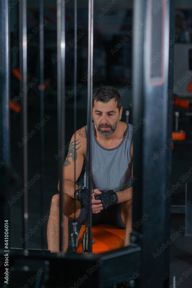 Fit mature man resting in between exercises in a gym Fit mature man resting in between exercises in a gym