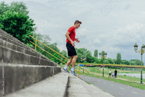 Fit male athlete performing stairs workout, running up climbing stairs performing outdoor track cardio..