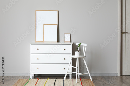 Interior of modern stylish room with chest of drawers and blank photo frames © Pixel-Shot