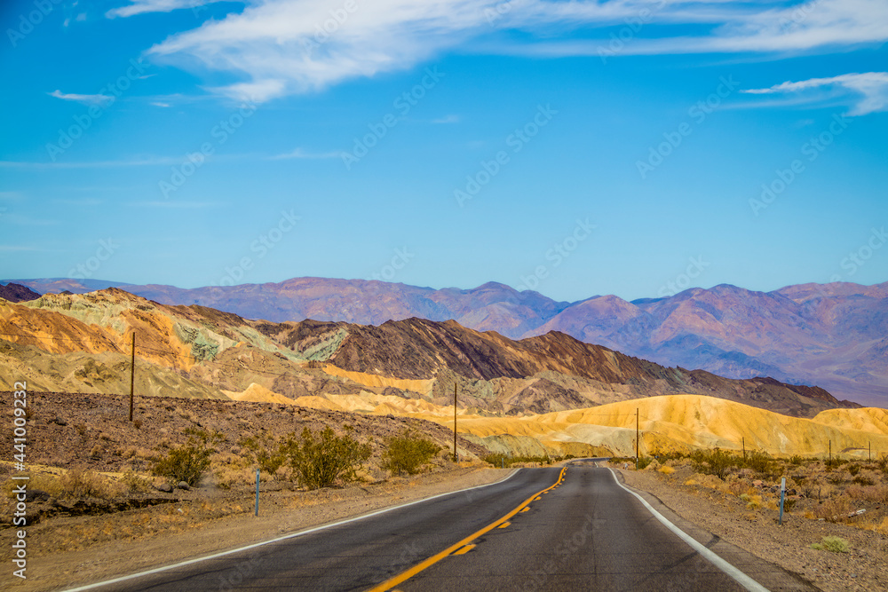 Two land black topped road through Death Valley California USA with multi-covered hills ahead - Geological rift valley and lowest point in North America