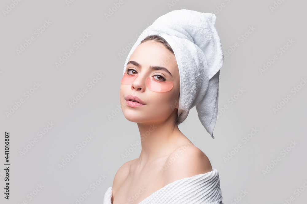 Woman applying eye patches. Close up portrait girl with towel on head. Portrait of beauty woman with eye patches showing an effect of perfect skin. Brunette spa girl applying anti-fatigue mask. Woman applying eye patches. Close up portrait girl with towel on head. Portrait of beauty woman with eye patches showing an effect of perfect skin. Brunette spa girl applying anti-fatigue mask.