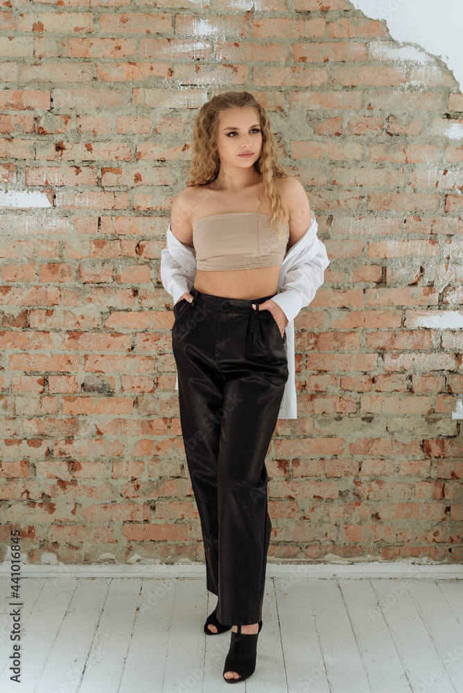 an attractive stylish young curly-haired female model in a short bra top and a white oversized shirt. trending fashionable women's clothing an attractive stylish young curly-haired female model in a short bra top and a white oversized shirt. trending fashionable women's clothing