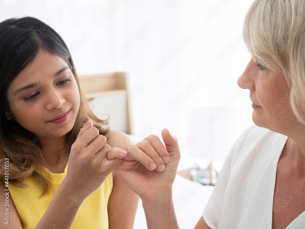 Asian teen daughter smile happily as reconcile with her adopted caucasian mother. love and sharing time of stepmother, stepdaughter concept. Asian teen daughter smile happily as reconcile with her adopted caucasian mother. love and sharing time of stepmother, stepdaughter concept.