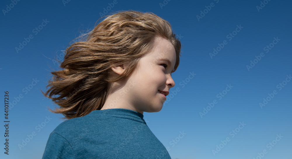 Funny child face on blue sky with copy space, close up. Kids looking away, head portrait. Funny child face on blue sky with copy space, close up. Kids looking away, head portrait.