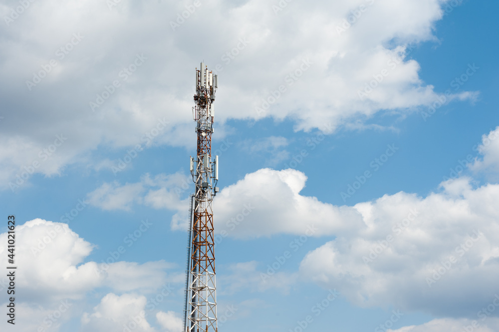 The tower with transmitter antennas on the cloudy sky background