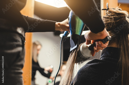 Photographie Master woman hairdresser dries the girl's hair with a hairdryer after washing in a beauty salon